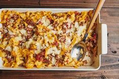 a casserole dish with meat, cheese and sauce in it on a wooden table