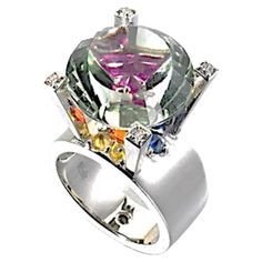 28.55 Carat Prasiolite Sapphire Diamond 18k White Gold Fashion Ring, In Stock. This fashion ring features a 28.55 carat prasiolite with a holographic cut. This stone was cut by Darryl Alexander. The ring also contains a 1.85 carat total weight of multi-colored sapphires and a 0.12 carat total weight of diamonds. The multi-colored sapphires are revealed through the table of the prasiolite, providing a kaleidoscope effect. Everything is hand-fabricated in 18 karat white gold. This prasiolite cocktail ring is a size 7. This garnet ring is a one-of-one jewelry design by the award-winning art jewelry designer Brenda Smith. Her work has been on the Red Carpet and in the Smithsonian Museum and won many awards. This ring is very characteristic of Brenda Smith’s signature art jewelry style. Her jew Smithsonian Museum, Creating Jewelry, Fashion Ring, Garnet Rings, Jewelry Companies, Gold Fashion, Sapphire Diamond, Cocktail Rings, Jewelry Art