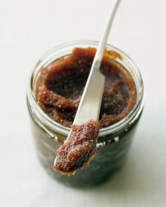 a spoon with some food in it on top of a glass jar filled with jam