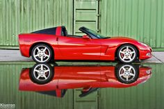 a red sports car parked in front of a green building