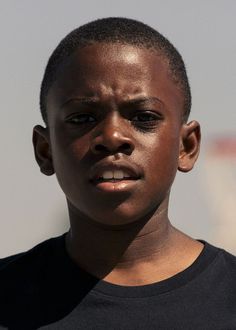 a close up of a person wearing a black t - shirt and looking at the camera