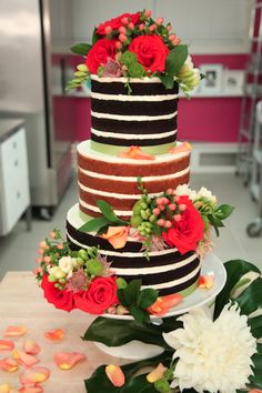 a multi - tiered cake with flowers and greenery sits on top of a table