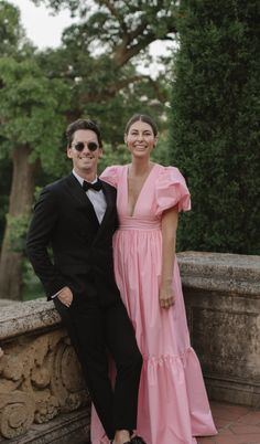 a man in a tuxedo and a woman in a pink dress pose for a photo