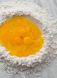 flour and eggs in a bowl on top of a marble countertop with white powder