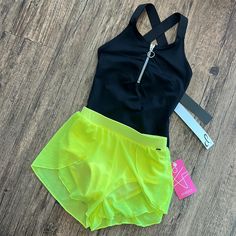 a black top and neon yellow shorts are on the floor next to a pair of scissors