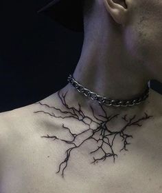 a man wearing a chain with branches attached to his chest and neck tattoo design on the back