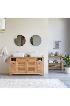 a bathroom with two sinks and mirrors on the wall next to a rug in front of it