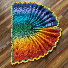 a multicolored crocheted doily sitting on top of a wooden floor