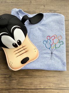 a blue shirt with a goofy face on the front and a mickey mouse mask on the back