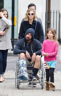 a man in a wheel chair being pushed by two women and children on the sidewalk