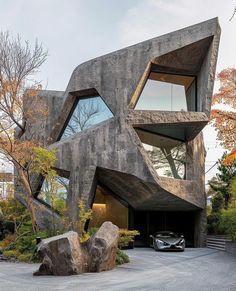 a car is parked in front of a building with two large rocks on the ground