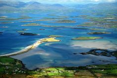 an aerial view of several islands in the ocean with green fields and blue water around them