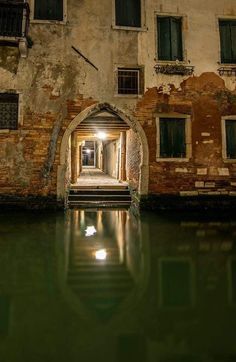 an arched doorway leading into a building next to a body of water in front of it