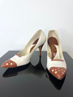 I am a sucker for a spectator, I have to admit, and these are so fab.   From the late 1950s or early 1960s with a painted egg-shell white base and a rusty brown toe cap, bow and heel.  Love the circle cutouts on the toe cap that are also white.  The heel is very narrow, spiked, and the toe box is pointed.  Leather sole.  Based on the insole, the colors are probably original but you can tell that the white is hand painted so it may have been done after market.  Adorable.      Label: Life Stride 8 Vintage White Heels For Wedding, Vintage White Heels With Round Toe, Vintage White Round Toe Heels, Vintage Closed Toe Heels With 4-inch Heel, Retro White Pointed Toe Heels, White Retro Heels With Pointed Toe, Vintage White Open Toe Heels, Vintage White High Heels, Retro Round Toe Heels For Wedding