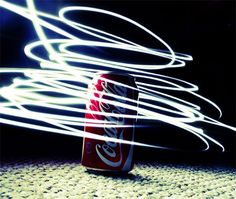 a can of coca - cola sitting on top of a floor next to white lines