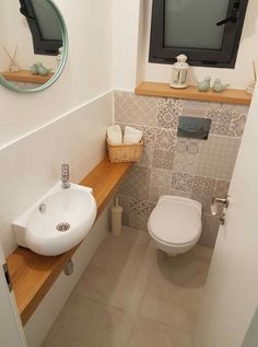 a bathroom with a toilet, sink and television on the wall in it's corner