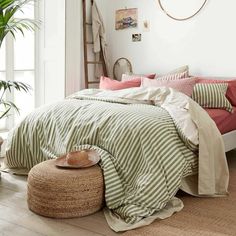 a bed with green and white striped bedspread in a bedroom next to a potted plant