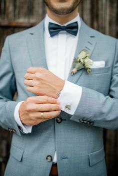 a man in a suit and bow tie adjusting his boutonniere on his lapel