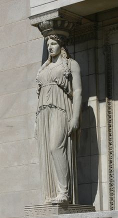 the statue is standing in front of the building's entrance door and has an elegant dress on it