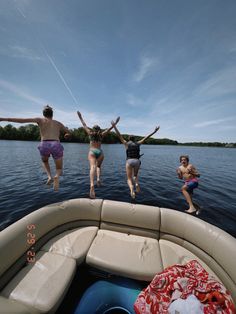 four people jumping into the air from a boat