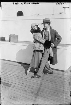 an old black and white photo of two people on a deck, one holding the other's hand