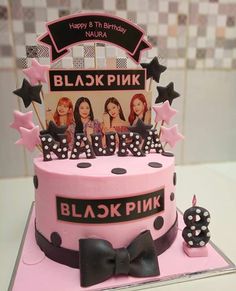 a pink birthday cake decorated with black and white polka dots, stars and the word blackpink on top