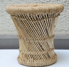 a large wicker vase sitting on top of a white table next to a wall