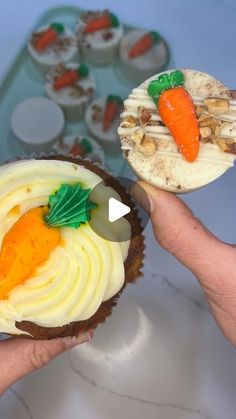 two cupcakes with carrots and nuts on them being held by someone's hand