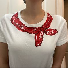 a woman wearing a white shirt and red bandanna around her neck is standing in front of a door