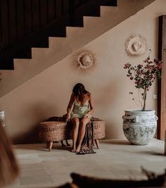 a woman sitting on top of a chair next to a vase with flowers in it