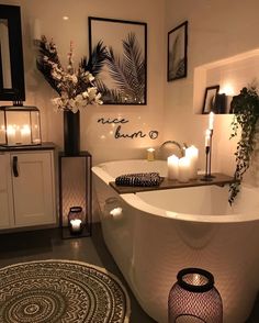 a bathtub with candles on the floor next to it and some pictures above it