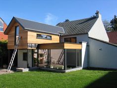 a house that has been built with wood and glass on the outside, while grass is in front of it