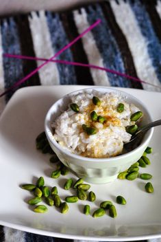 a white bowl filled with rice and peas on top of a plate next to a spoon