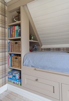 a bed sitting under a window next to a book shelf