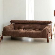 a brown couch sitting next to a wooden table and chair in a room with white walls