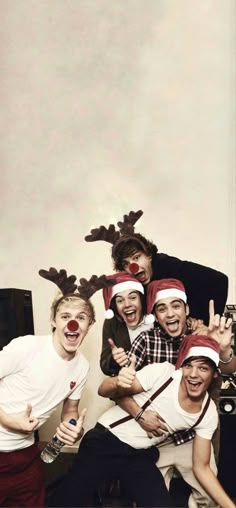 a group of young men standing next to each other wearing reindeer antlers on their heads