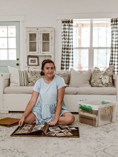 a woman is sitting on the floor in front of a couch with pictures and books