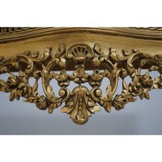 an ornately carved gold headboard with flowers and leaves on the top, against a blue background