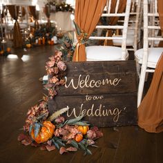 a welcome sign sitting on top of a wooden crate filled with flowers and greenery