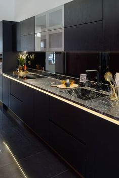 a black kitchen with marble counter tops and gold accents on the sink, along with dark wood cabinets