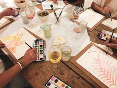 people sitting around a table with paintings and watercolors