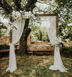 an outdoor wedding ceremony with white flowers and draping