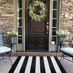 a black and white striped rug in front of a door with two chairs on it