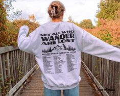 "This Unisex crewneck sweatshirt features \"Not All Who Wander Are Lost | Explore Our U.S. National Parks | I Have Visited:\" with a complete list of the 63 U.S. National Parks on the back. You can actually bubble in the parks you have visited with fabric markers (white or black) and it's the perfect gift for adventurers! Make sure to check out the other garment options below :) » O P T I O N S « ‣ Hoodie: https://www.etsy.com/listing/1343910283 » A B O U T « ‣ This item is made to order using d Fall Outdoor Crew Neck Sweatshirt, Fall Crew Neck Sweatshirt For Outdoor, Crew Neck Slogan T-shirt For Fall, Fall Hoodie With Text Print And Crew Neck, Fall Crew Neck Hoodie With Text Print, Fall Slogan Hoodie With Crew Neck, Fall Slogan Crew Neck Hoodie, Fall Band Merch Sweatshirt With Text Print, Band Merch Crew Neck Sweatshirt With Text Print