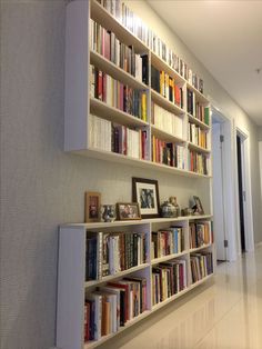 a bookshelf filled with lots of books next to a white door in a room