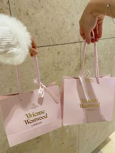 two pink shopping bags being held by someone's hand