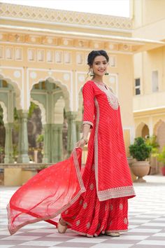 This Red Rayon Leheriya Embroidered Sharara Suit features a long kurta with Zari and Sequins embroidery accents on the yoke, sleeves, and hemline. The suit includes a coordinating sharara and a printed chiffon dupatta with an embroidered border for a unique, elegant look. Perfect for special occasions. Color: Red Top: Rayon Bottom: Rayon Dupatta: Chiffon Top Length: 46" Bottom Length: 41" Dupatta Size: 2.2 m Occasion: Festive Print-Pattern: Leheriya Ornamentation: Zari Shape: Straight Design Sid Transitional Red Kurta With Dori Work, Red Straight Kurta With Dori Work, Red Palazzo Set With Chikankari Embroidery And Straight Kurta, Red Sharara With Straight Kurta For Traditional Ceremonies, Red Straight Kurta Sharara For Traditional Ceremonies, Red Semi-stitched Palazzo Set For Festivals, Festive Red Sets With Dori Work, Red Salwar Kameez With Dori Work Straight Kurta, Red Traditional Straight Kurta With Dupatta