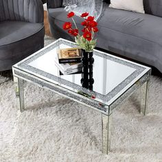 a living room with two gray couches and a mirrored coffee table in the middle