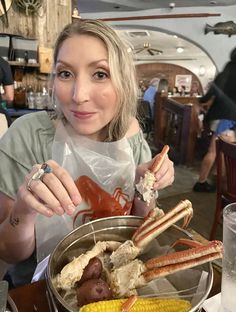 a woman sitting at a table with food in front of her and holding a fork