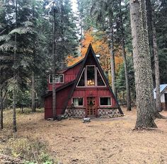 a red cabin in the woods surrounded by trees